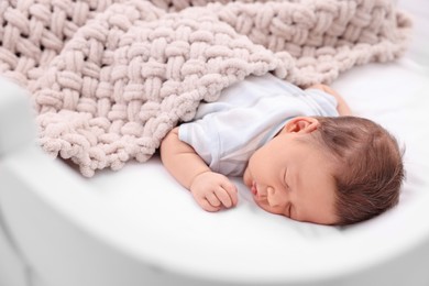 Cute newborn baby sleeping under plaid in crib