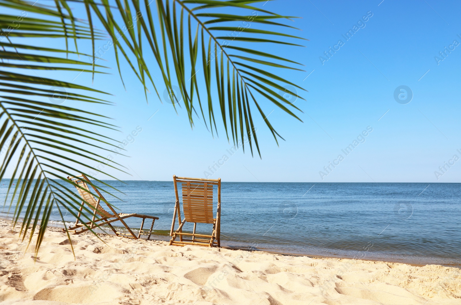 Photo of Sandy beach with empty wooden sunbeds on sunny day