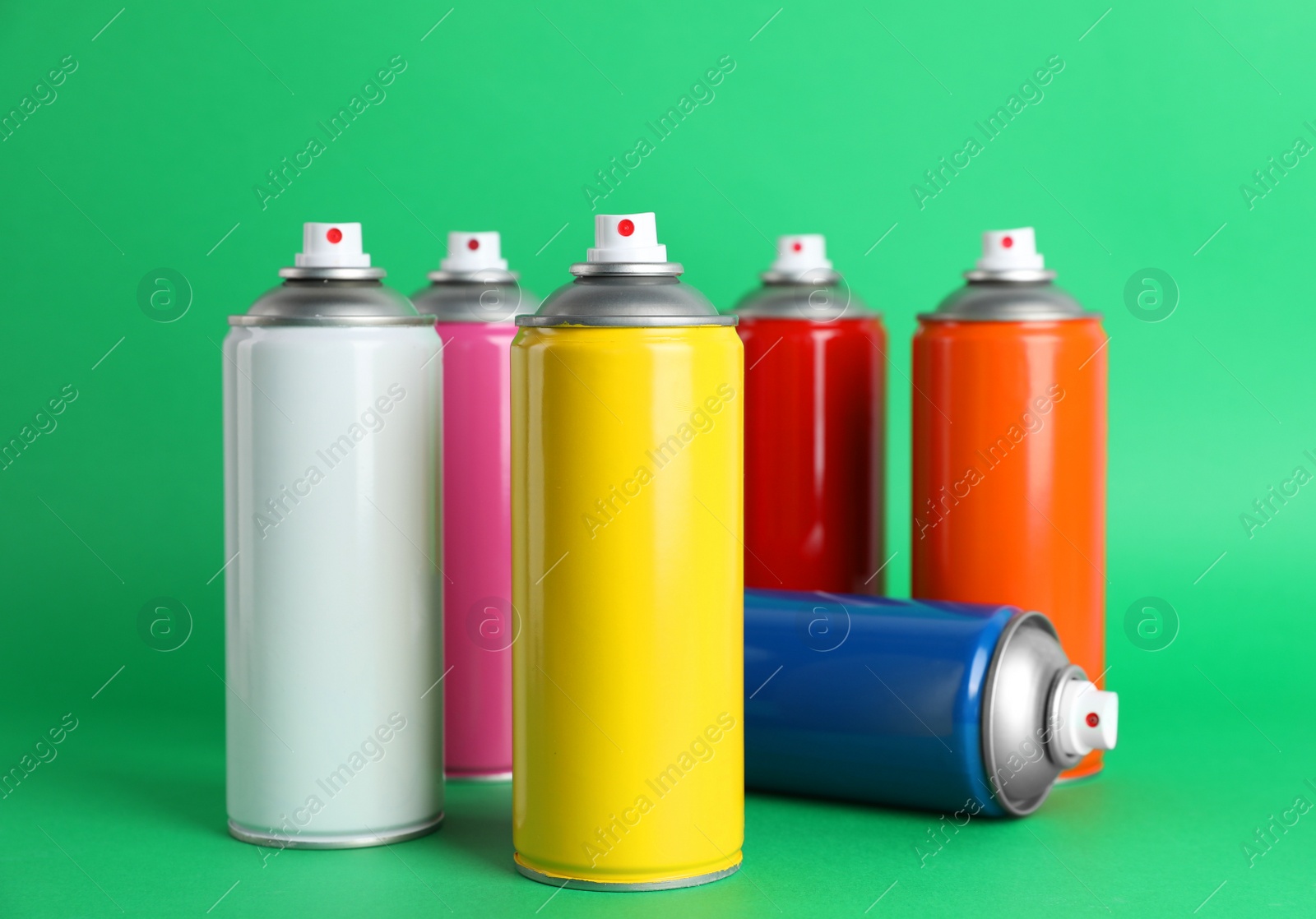 Photo of Colorful cans of spray paints on green background