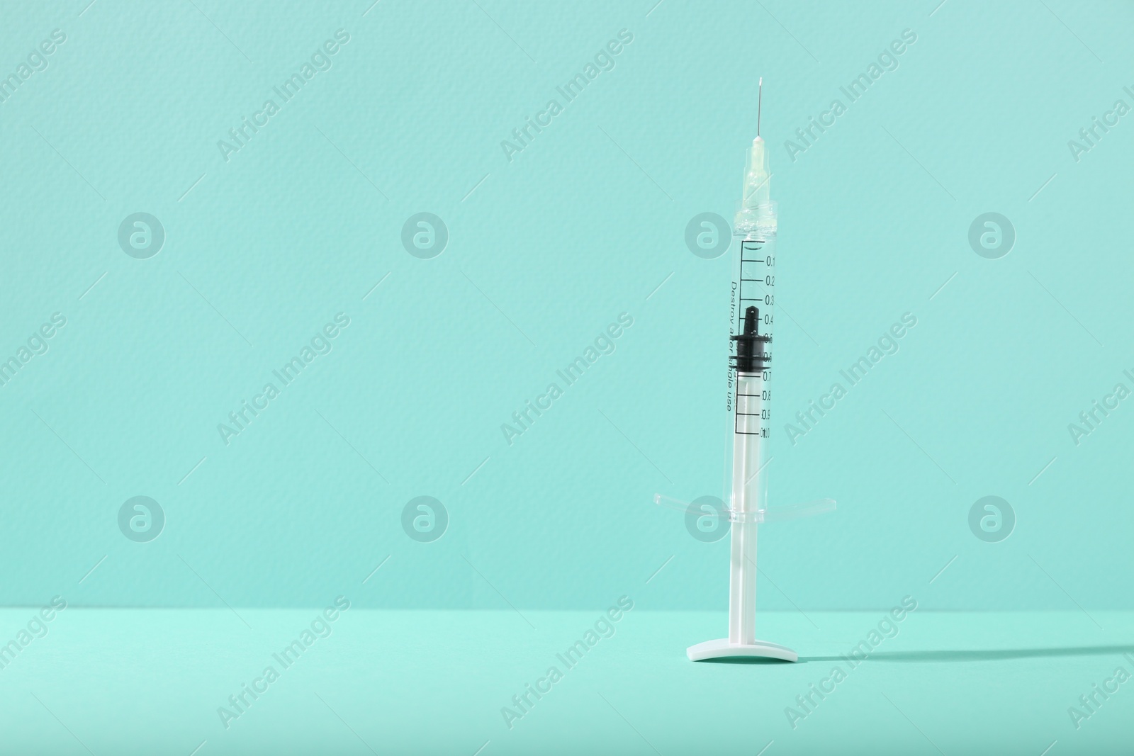 Photo of Cosmetology. Medical syringe on turquoise background, space for text