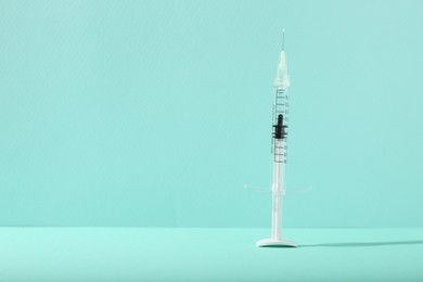 Cosmetology. Medical syringe on turquoise background, space for text