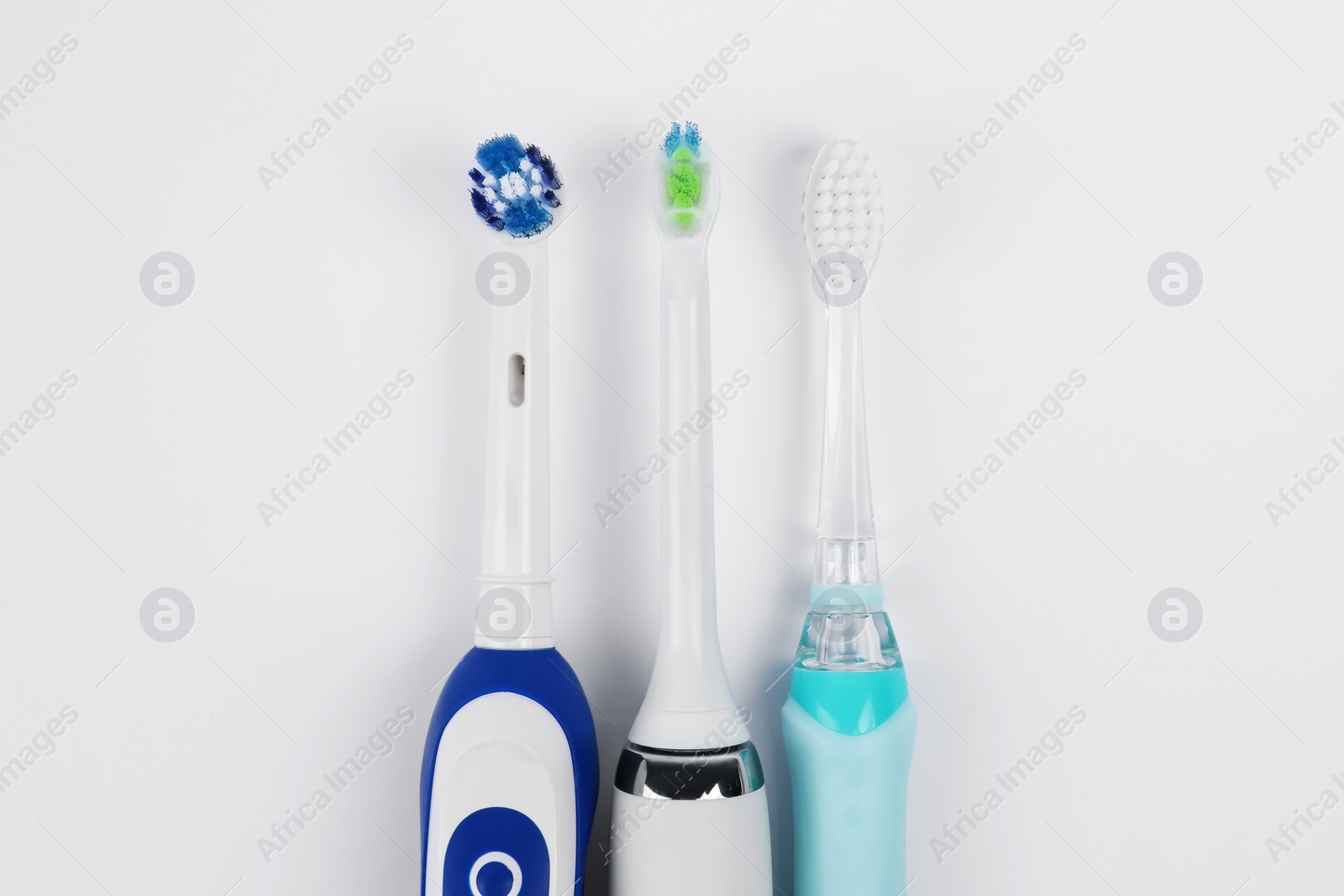Photo of Electric toothbrushes on white background, flat lay
