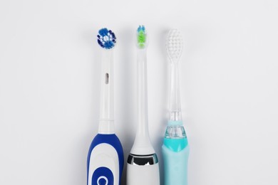 Photo of Electric toothbrushes on white background, flat lay