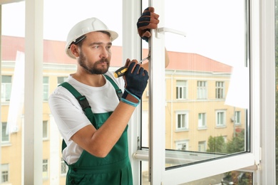 Construction worker installing new window in house