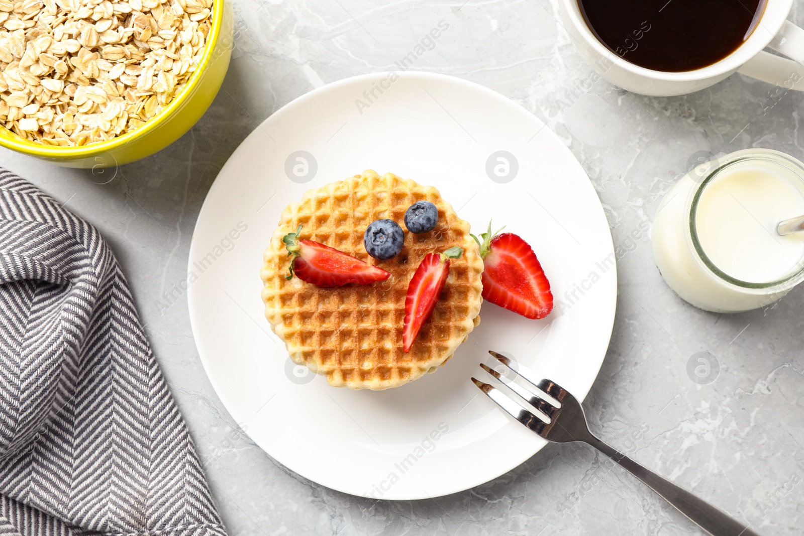 Photo of Tasty breakfast with wafers served on light grey marble table, flat lay