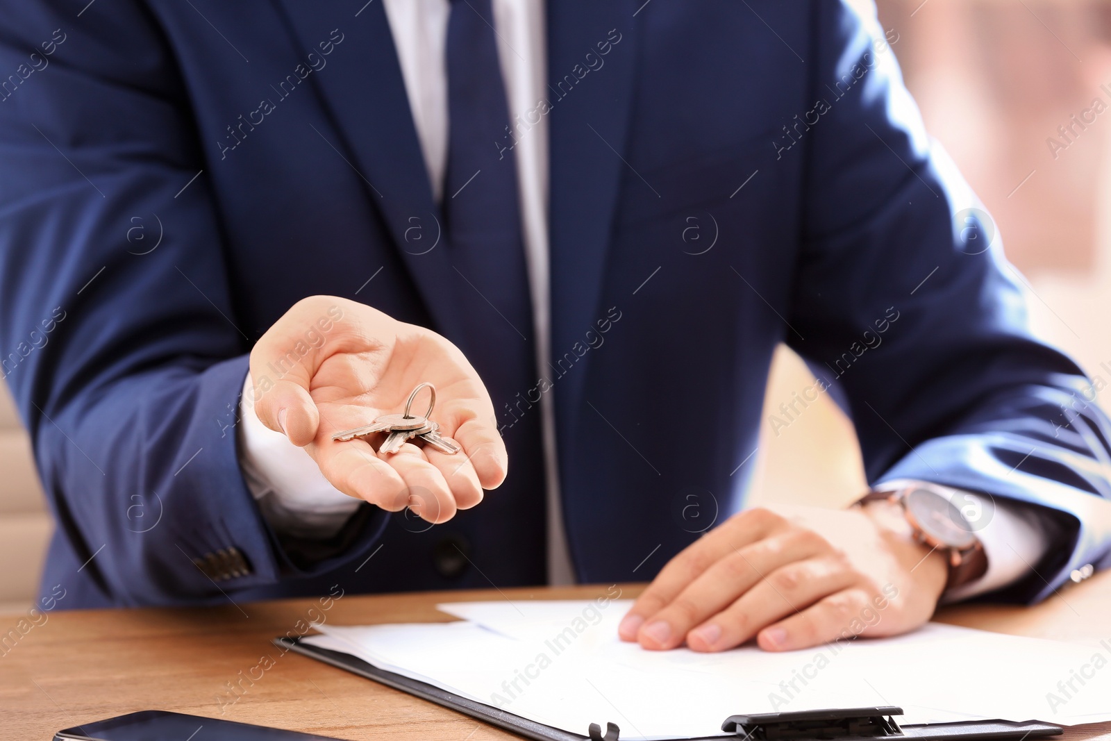 Photo of Real estate agent with keys at table in office, closeup