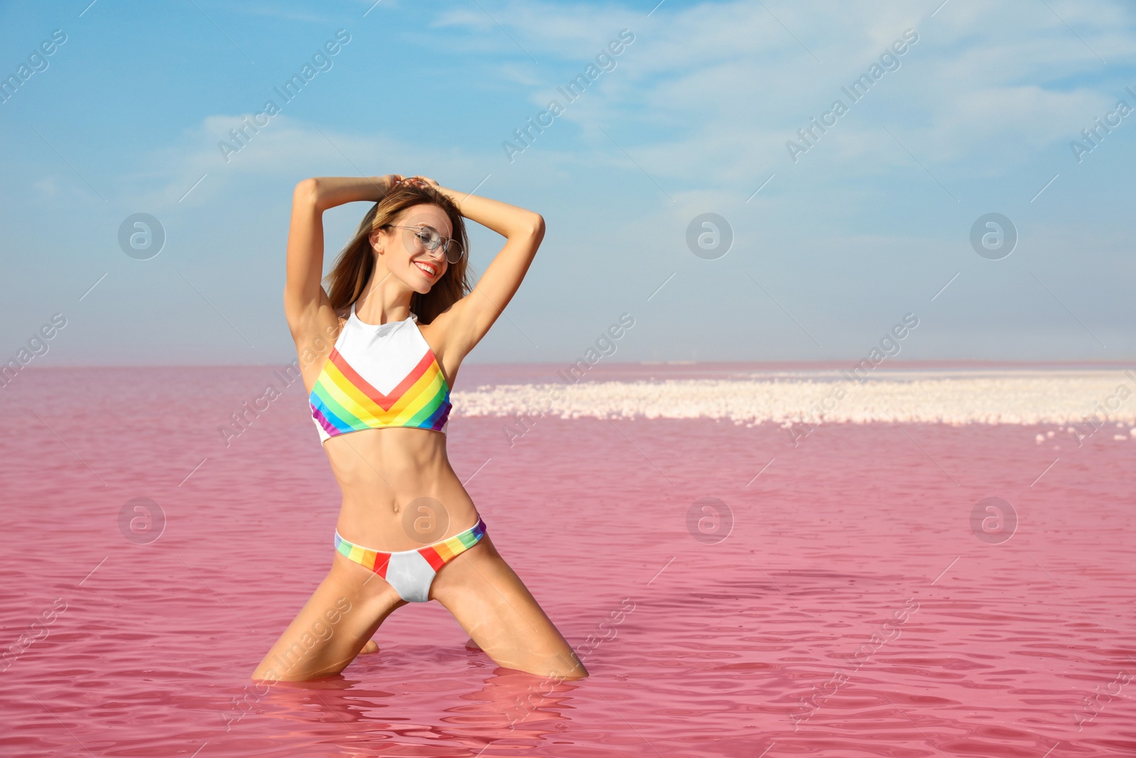 Photo of Beautiful woman posing in pink lake on sunny day