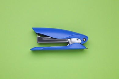 New bright stapler on green background, top view. School stationery