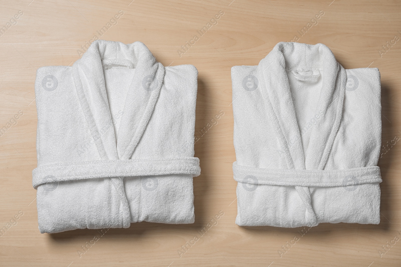 Photo of Flat lay composition with folded bathrobes on wooden background