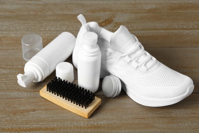 Composition with stylish footwear and shoe care accessories on wooden background