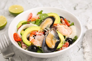 Photo of Bowl of delicious salad with seafood on white textured table, closeup