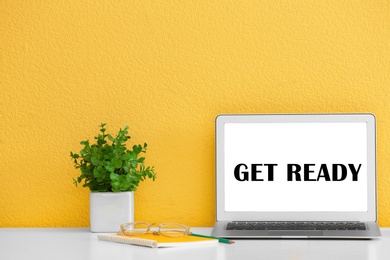 Image of Modern laptop with phrase Get Ready on screen near yellow wall