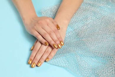 Woman showing manicured hands with golden nail polish on color background, closeup. Space for text