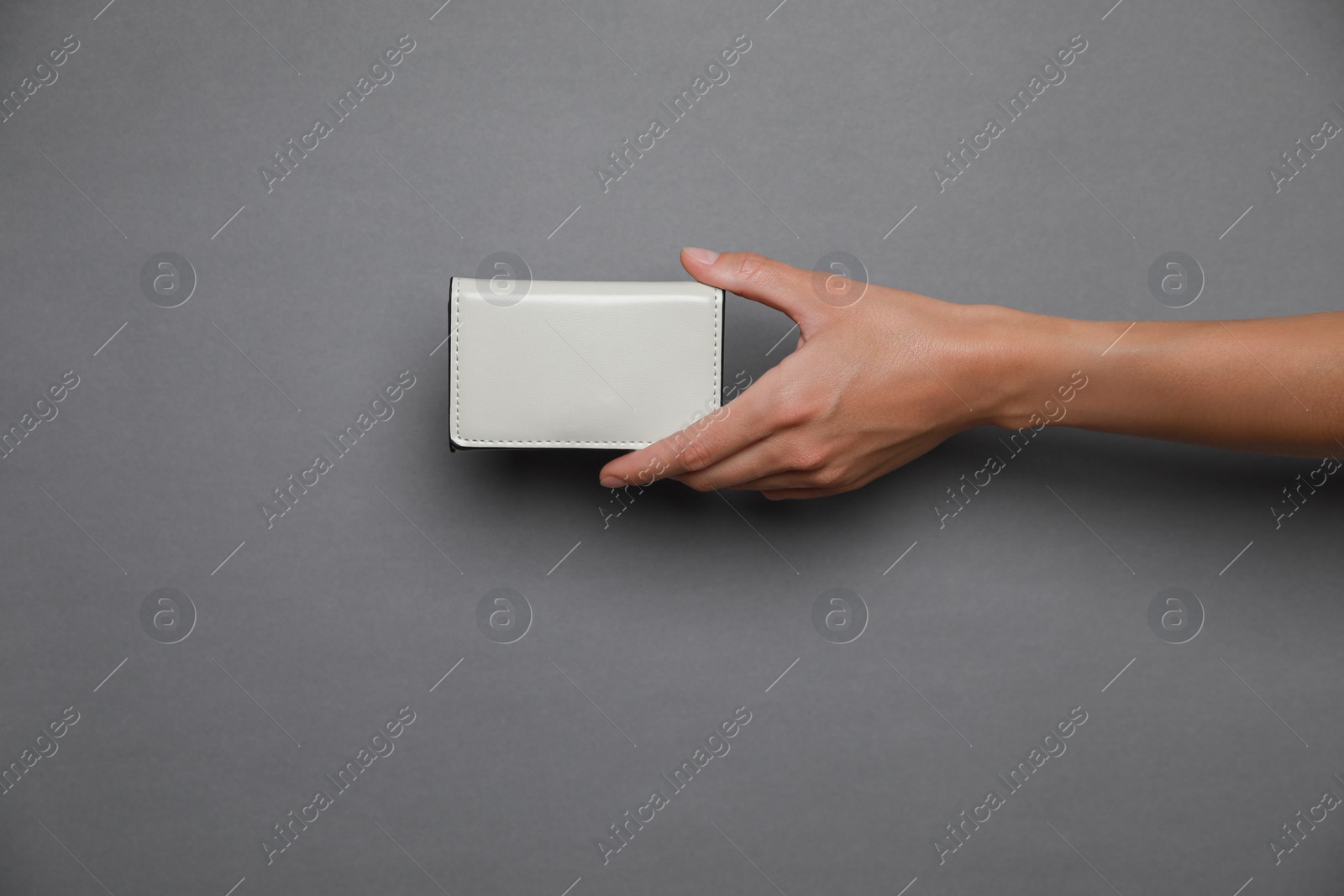 Photo of Woman holding white purse on dark grey background, closeup. Space for text