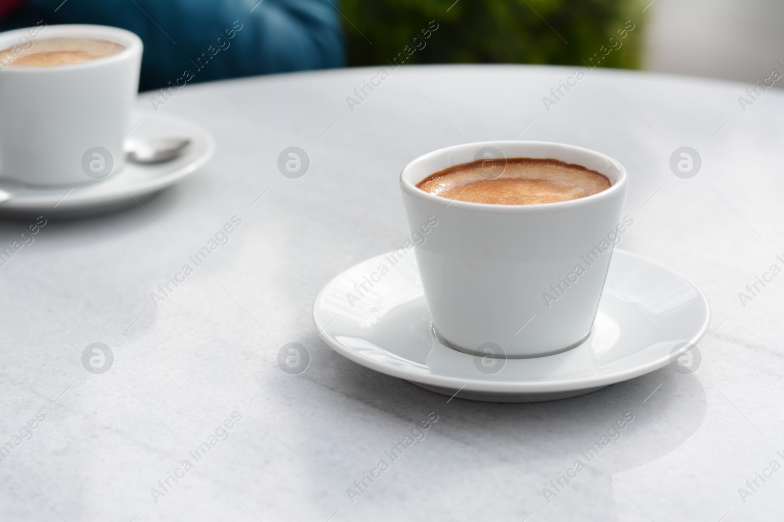 Photo of Ceramic cups of aromatic coffee with foam on table in morning