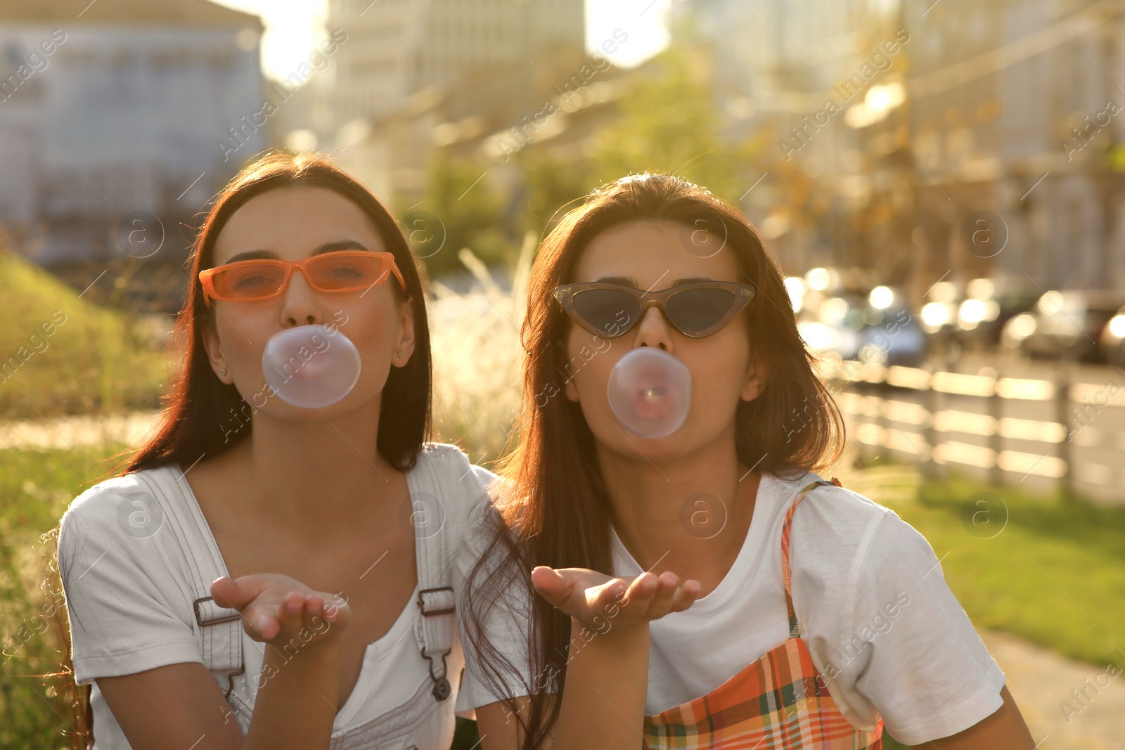 Photo of Beautiful women in sunglasses blowing gums outdoors