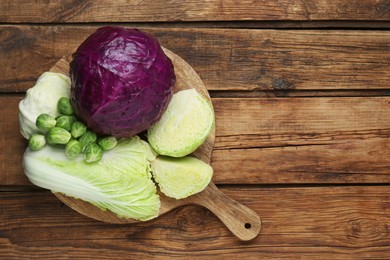 Photo of Different types of cabbage on wooden table, top view. Space for text