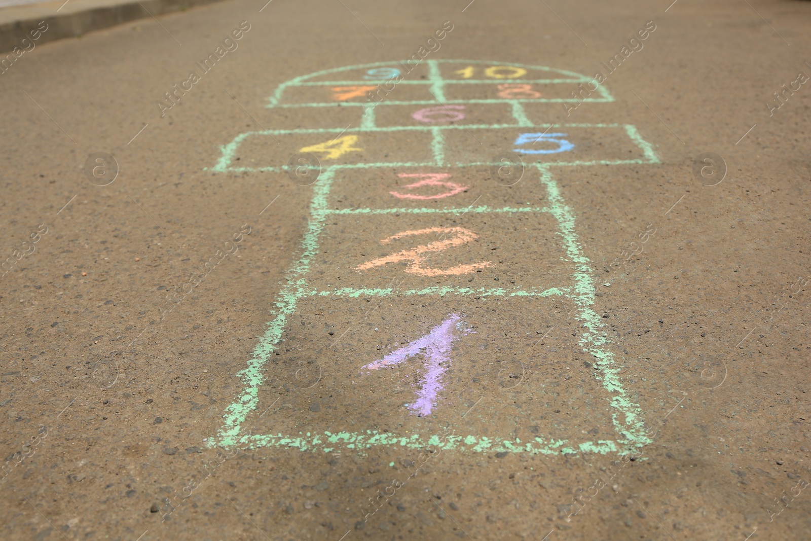 Photo of Hopscotch drawn with colorful chalk on asphalt outdoors, closeup