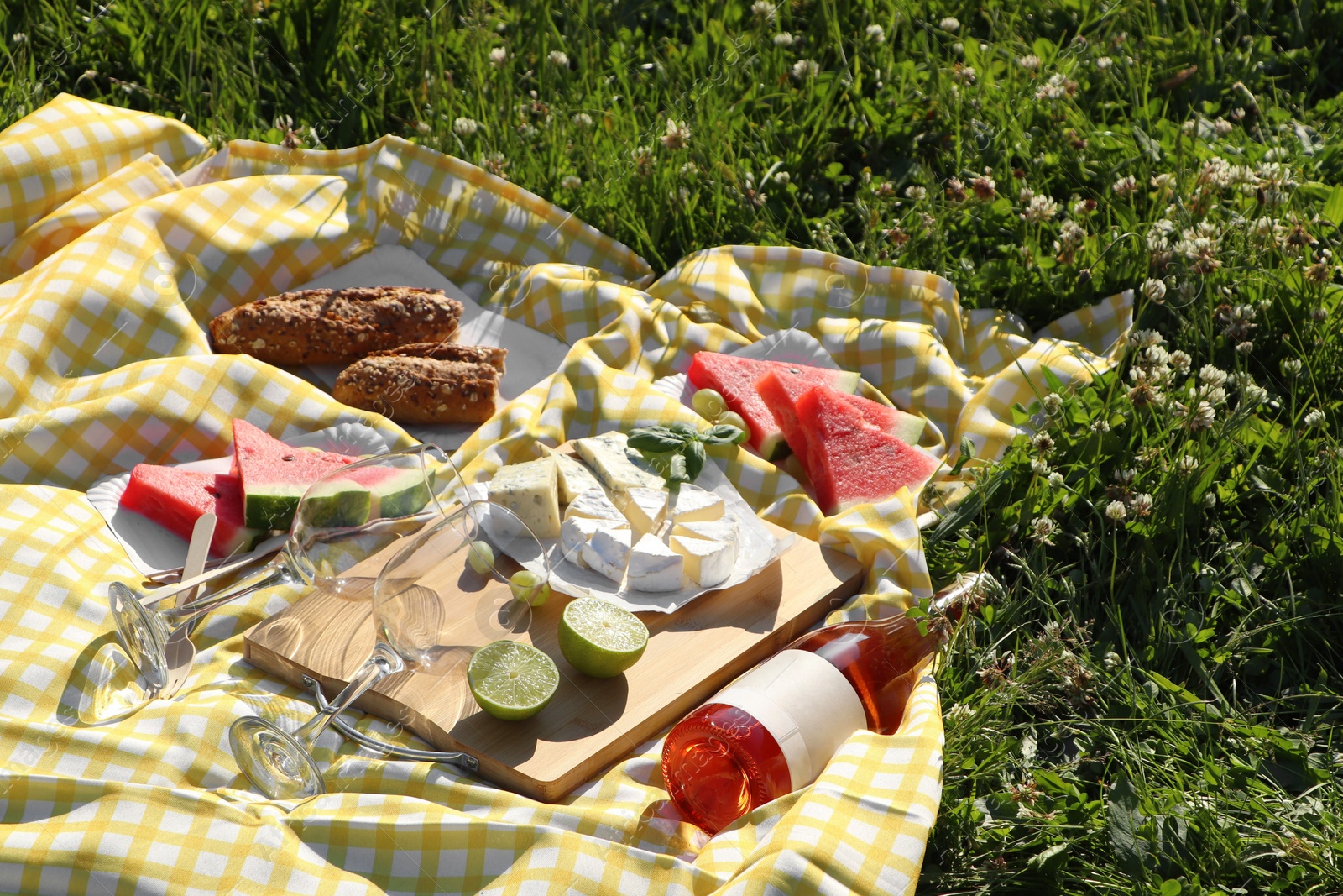 Photo of Picnic blanket with delicious food and wine on green grass outdoors