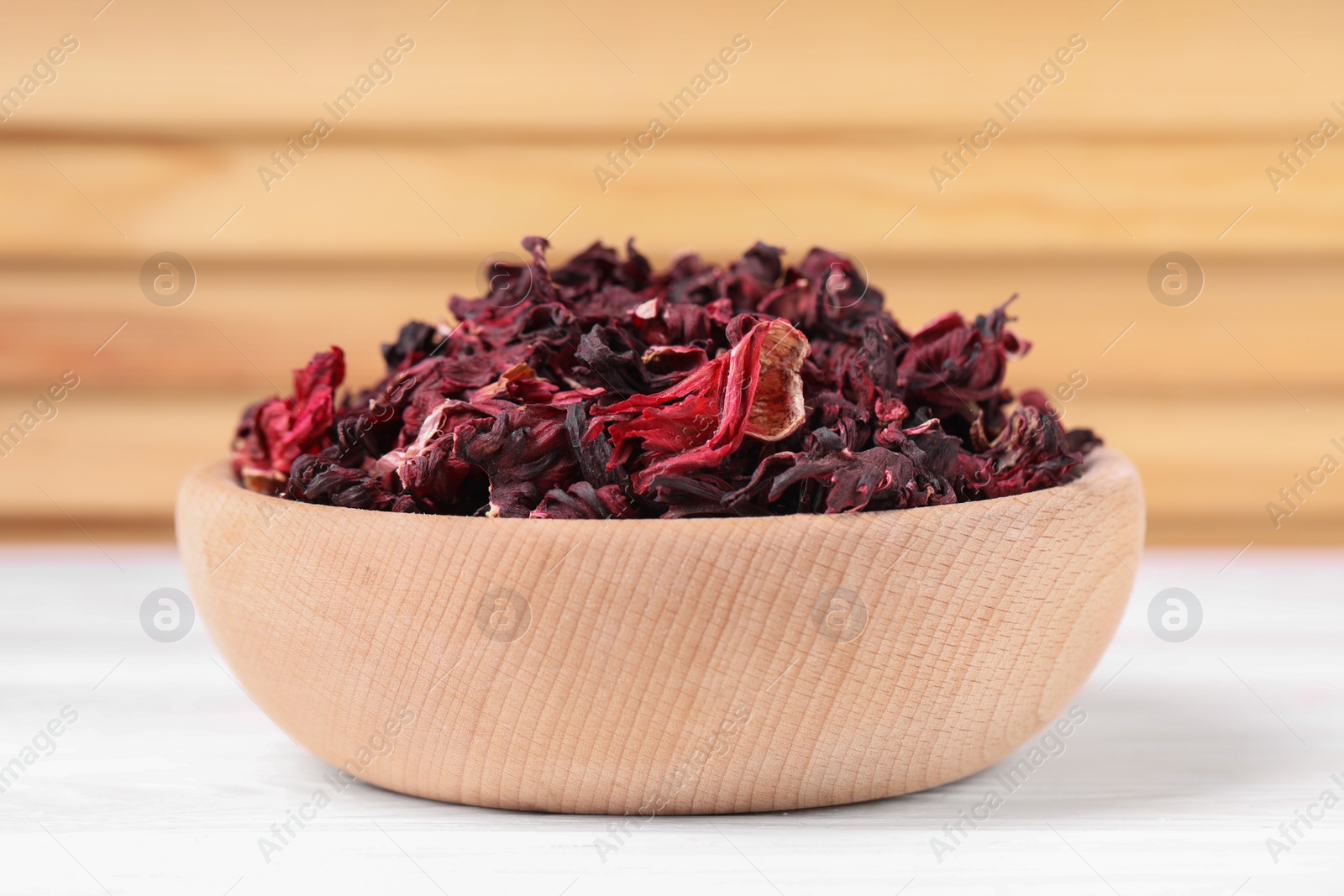 Photo of Dry hibiscus tea in bowl on white table, closeup