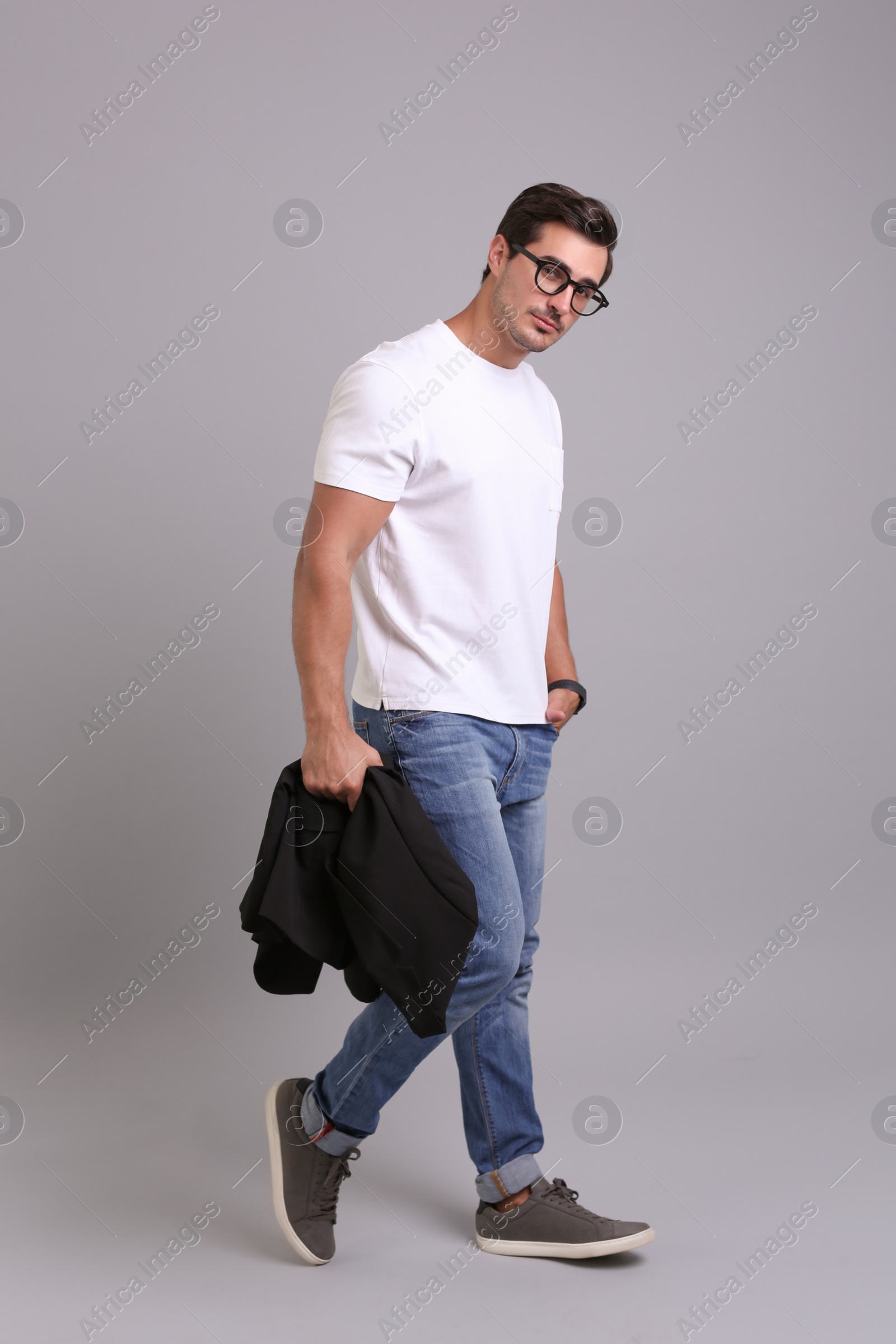 Photo of Handsome young man in casual clothes with black jacket and glasses on grey background