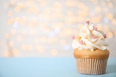 Photo of Tasty cupcake on table against blurred lights, space for text. Valentine's Day celebration