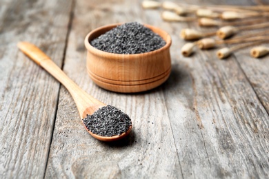 Bowl and spoon with poppy seeds on wooden table