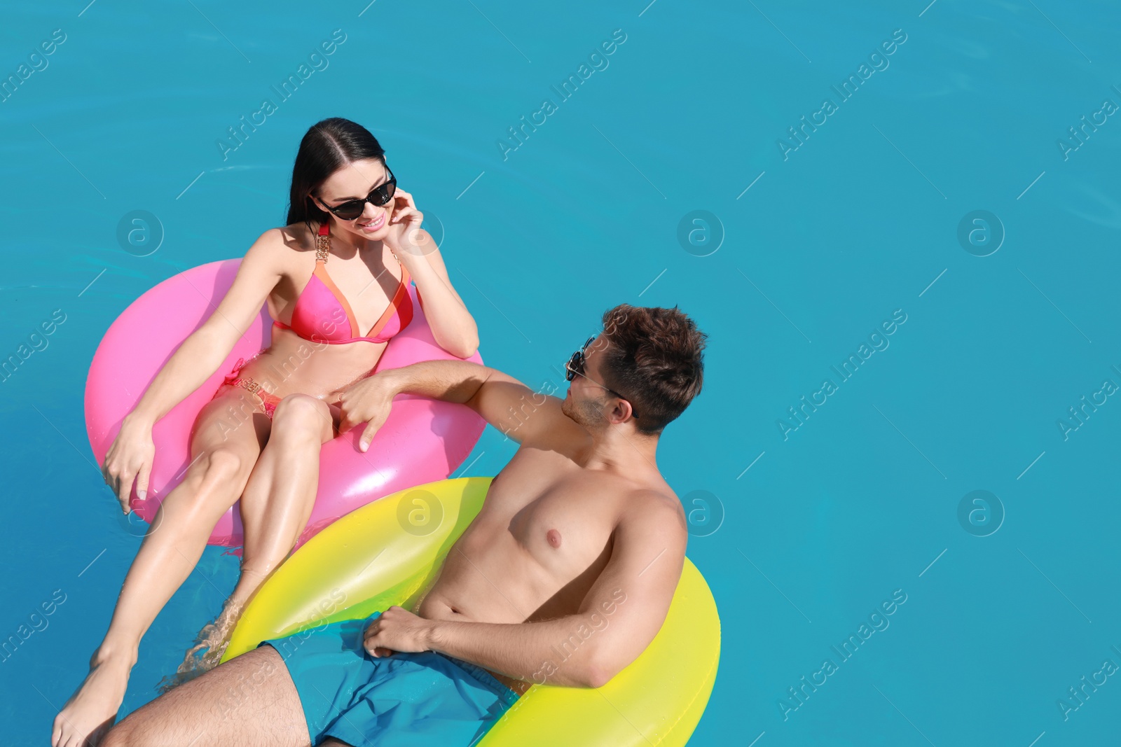 Photo of Woman in bikini with boyfriend swimming at resort. Happy young couple