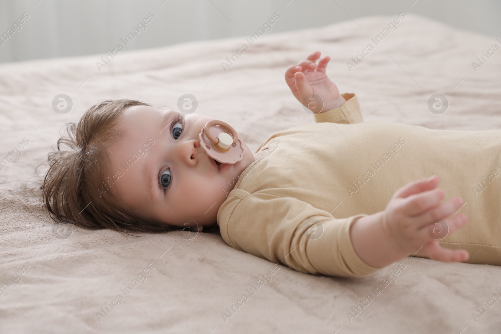 Photo of Cute little baby with pacifier on bed indoors