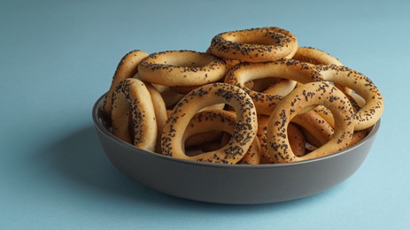 Photo of Bowl with delicious ring shaped Sushki (dry bagels) on light blue background