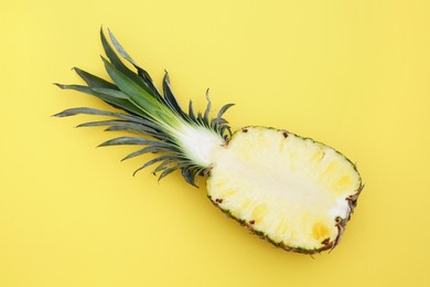 Half of ripe pineapple on yellow background, top view