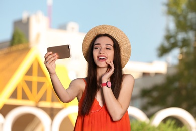 Photo of Happy young woman taking selfie outdoors on sunny day