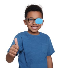 Photo of African American boy with eye patch on glasses showing thumb up against white background. Strabismus treatment