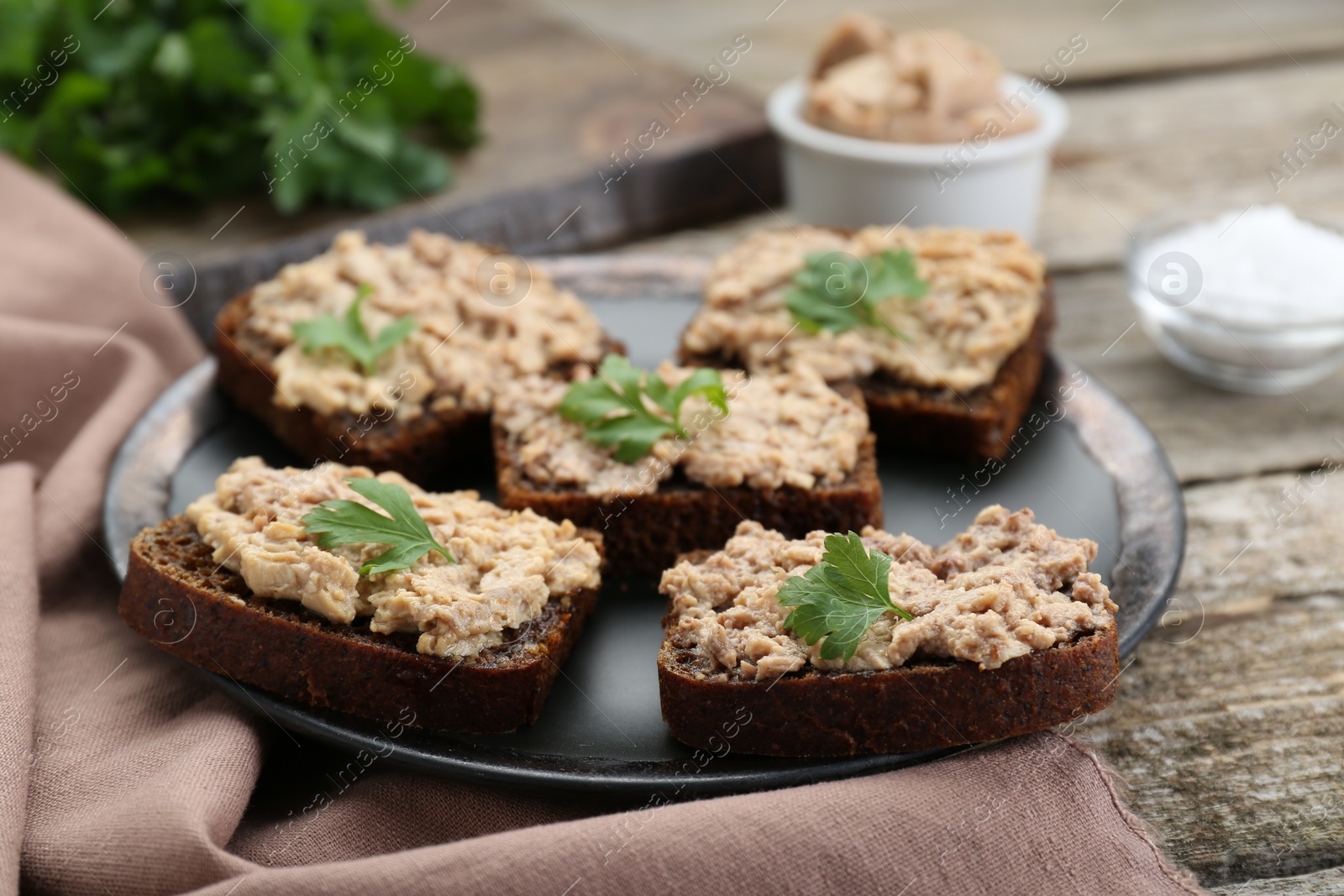 Photo of Tasty sandwiches with cod liver and parsley on wooden table