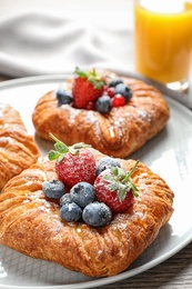 Fresh delicious puff pastry with sweet berries on table, closeup