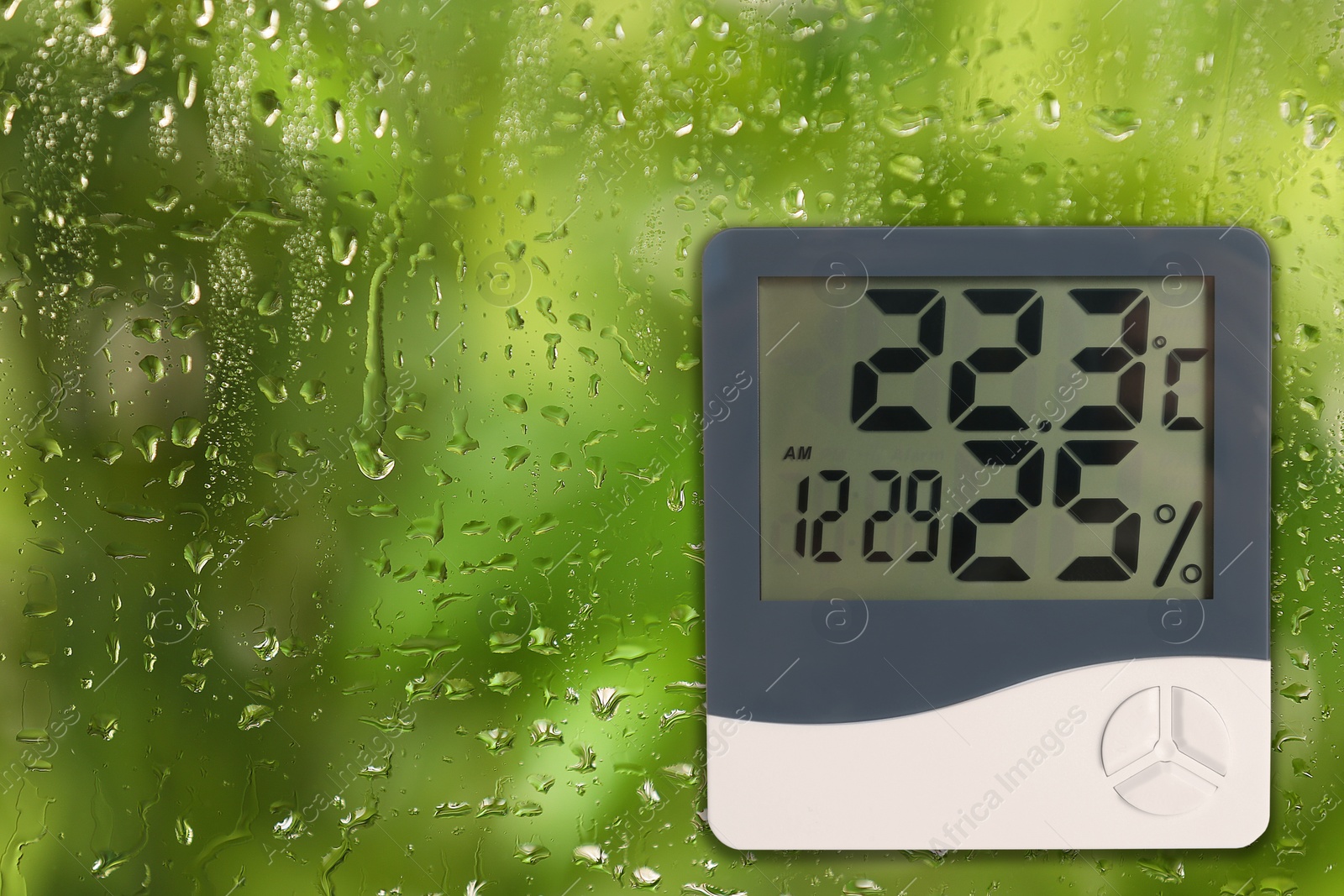 Image of Digital hygrometer with thermometer on glass with water drops. Space for text