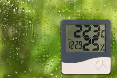 Image of Digital hygrometer with thermometer on glass with water drops. Space for text