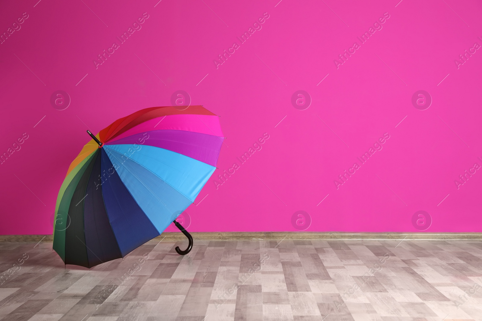 Photo of Beautiful open umbrella on floor near color wall with space for design