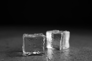 Photo of Ice cubes with water drops on grey stone table, closeup