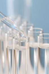 Photo of Laboratory analysis. Dripping liquid from pipette into glass test tube on blurred background, closeup