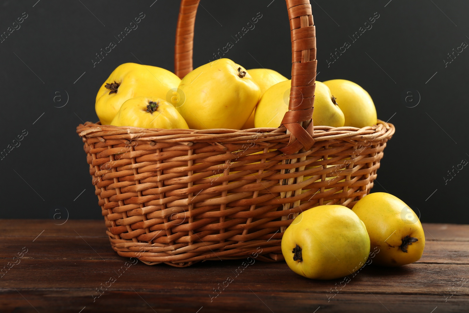 Photo of Basket with delicious ripe quinces on wooden table