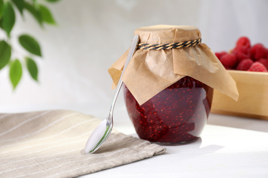 Delicious raspberry jam in jar on white table