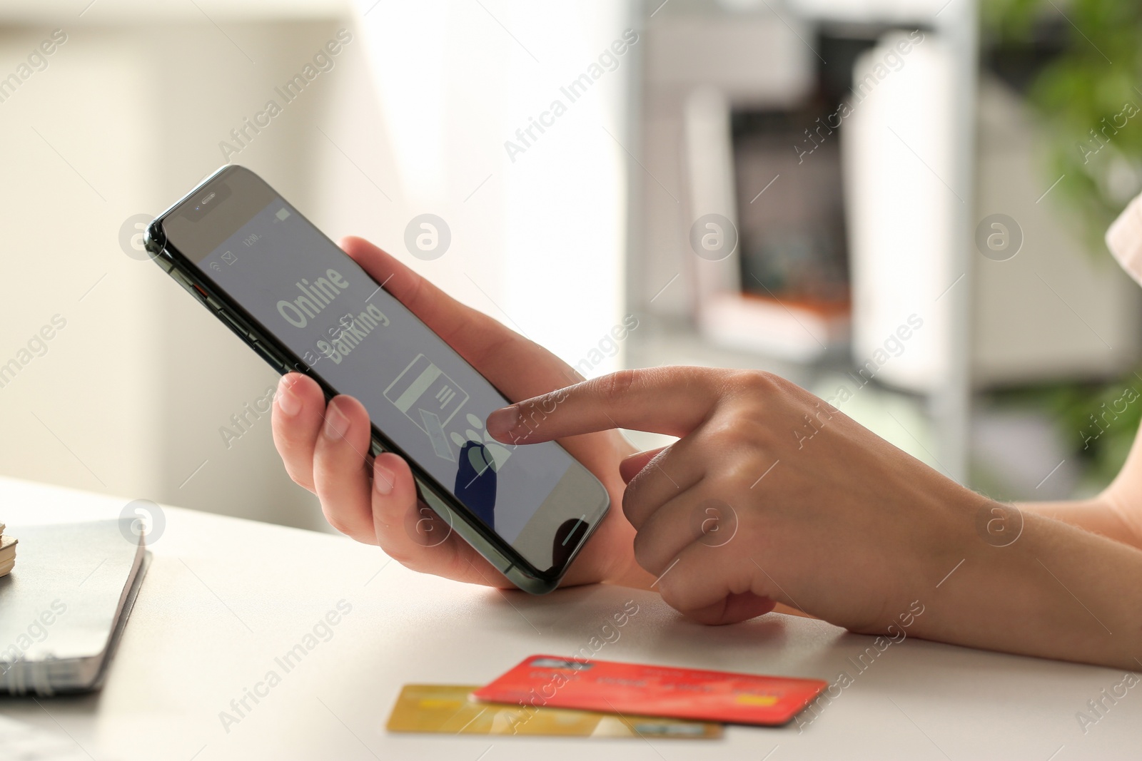 Photo of Woman using online banking app on smartphone at white office table, closeup