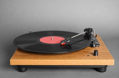 Photo of Modern vinyl record player with disc on grey background