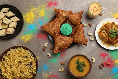 Traditional Indian food and color powders on grey table, flat lay. Holi festival celebration