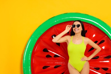 Photo of Young woman with stylish sunglasses near inflatable mattress against orange background