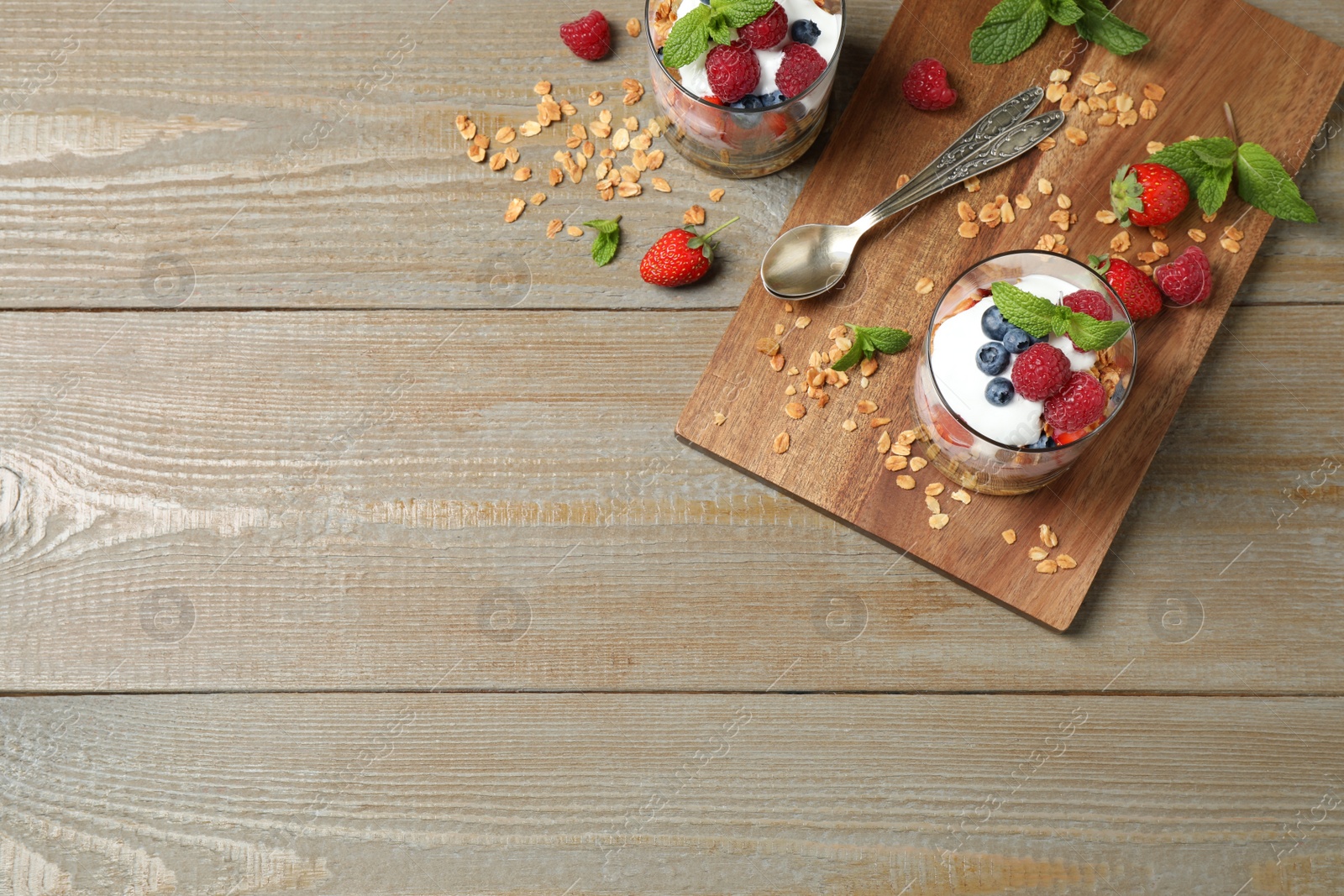 Photo of Healthy homemade granola dessert served on wooden table, flat lay. Space for text