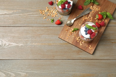 Photo of Healthy homemade granola dessert served on wooden table, flat lay. Space for text