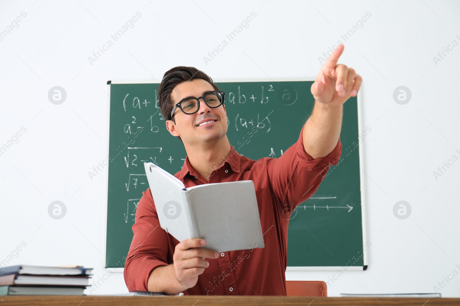 Photo of Young teacher working at table in classroom