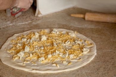 Photo of Pizza dough with cheese on table. Oven recipe